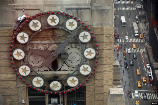 A worker replaces some lightbulbs around a clock above Times Square on the Paramount building in New York City. Photo Credit: Reuters